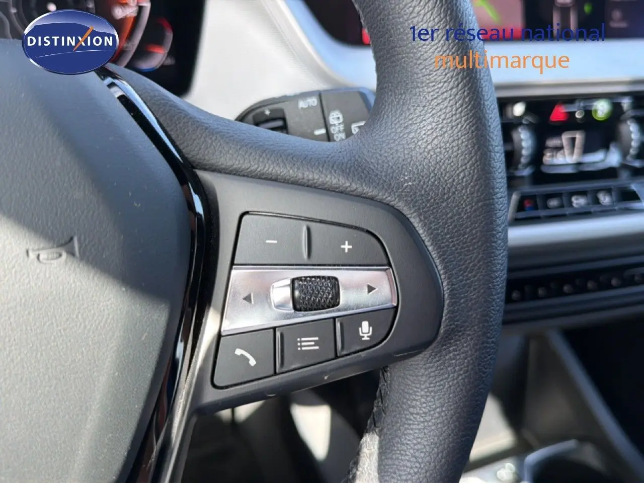 Gros plan sur les commandes au volant en cuir noir de la BMW Série 1 116i 2022, avec tableau de bord flou en arrière-plan.