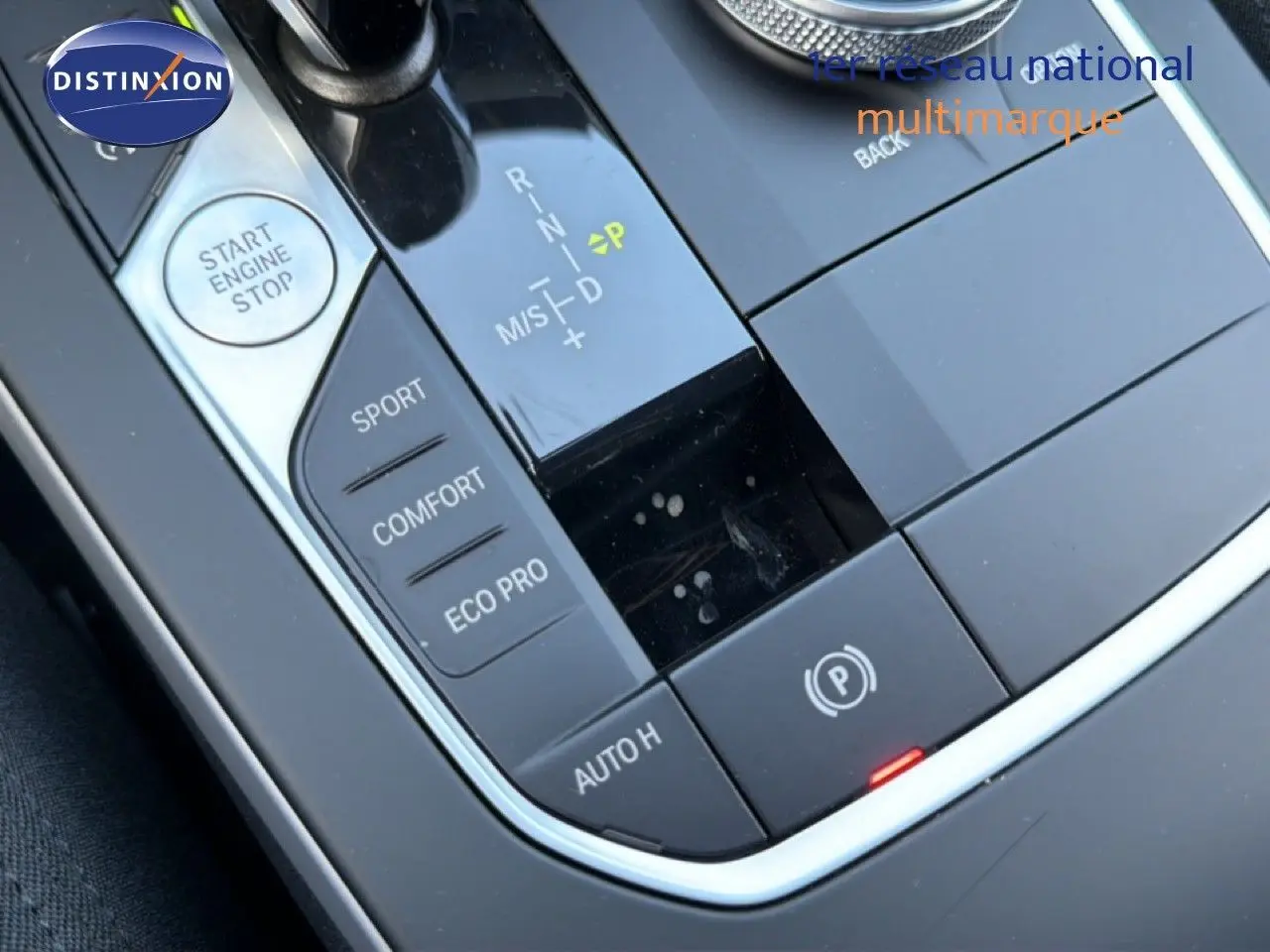 Gros plan sur la console centrale noire de la BMW Série 1 116i 2022, montrant le levier de vitesses automatique et les modes de conduite.