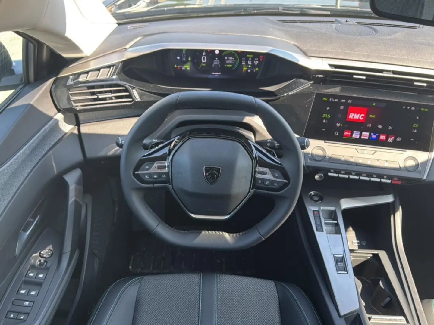 Vue intérieure centrée sur le volant cuir et le tableau de bord numérique du Peugeot 408 Hybrid 145 allure noir.