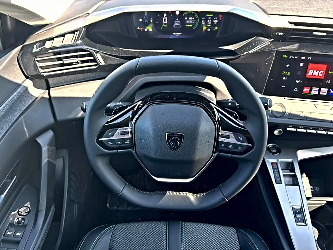 Vue intérieure centrée sur le volant cuir noir et le tableau de bord numérique de la Peugeot 408 Hybrid 145 allure 2025.