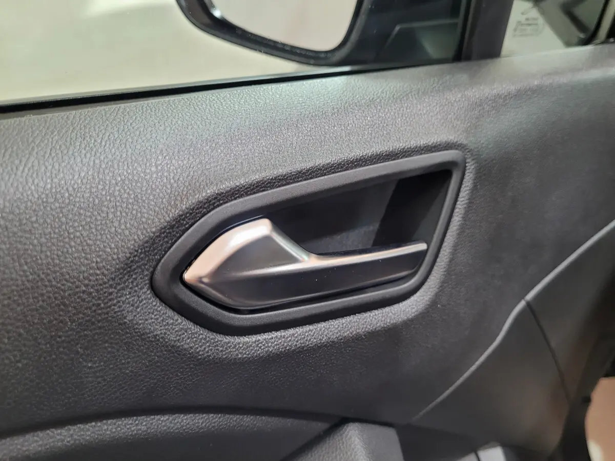 Poignée intérieure de porte côté droit de la Renault Clio gris foncé, avec finition plastique texturée noire.