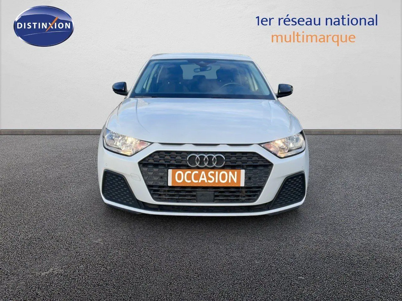 Vue de face d'une Audi A1 Sportback blanche glacier métal avec calandre noire et plaque "OCCASION" orange.