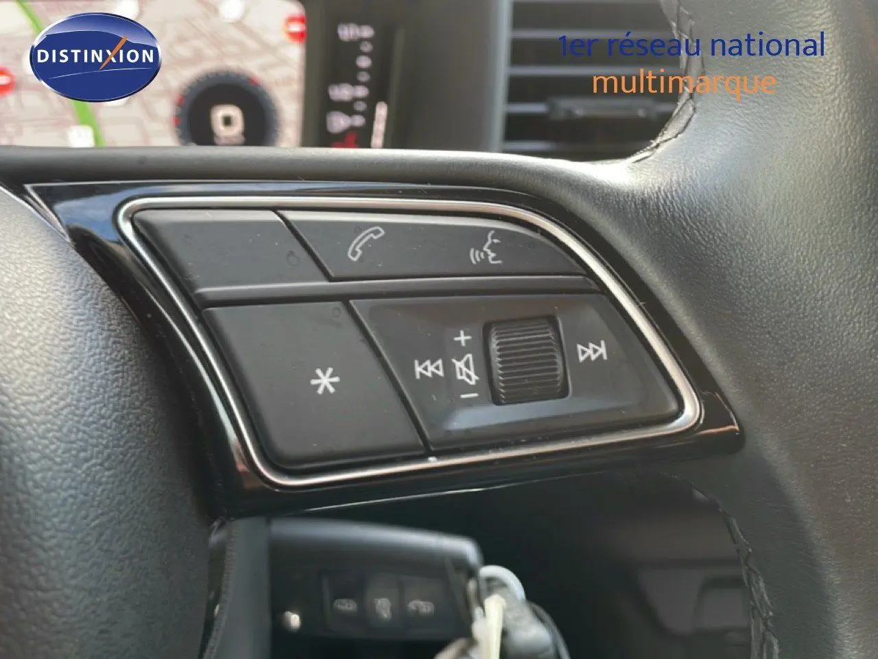 Gros plan sur les commandes audio et téléphone intégrées au volant noir de l'Audi A1 Sportback blanc glacier 2023.