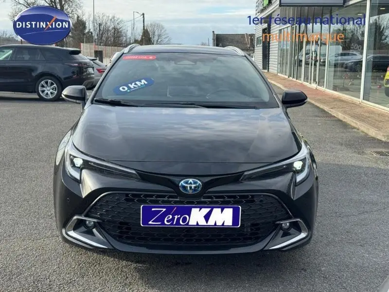 Vue avant d'une Toyota Corolla noire 2025 avec calandre large et feux LED allumés sur parking.