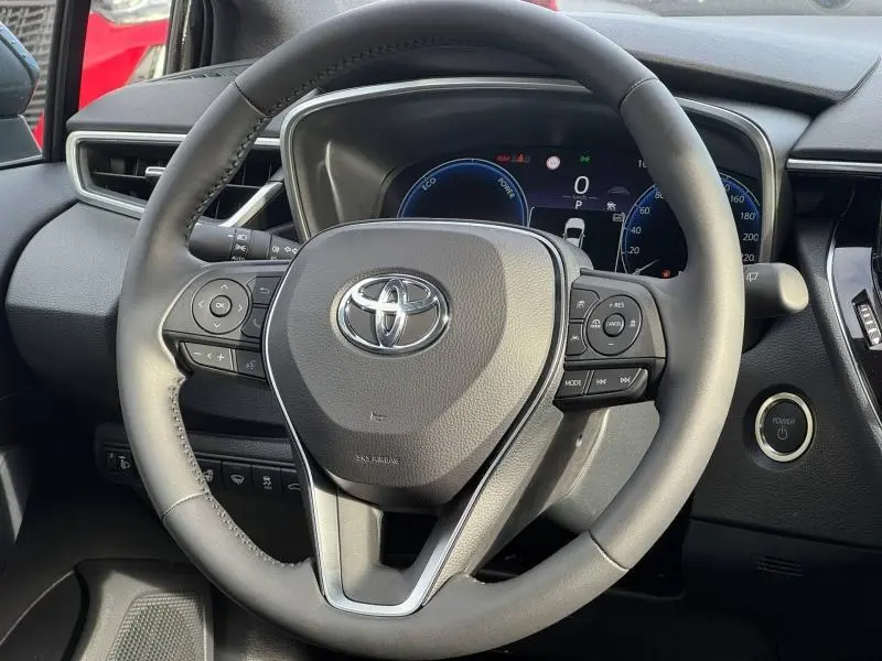 Vue rapprochée du volant cuir multifonction d'une Toyota Corolla 2025, avec tableau de bord digital en arrière-plan.