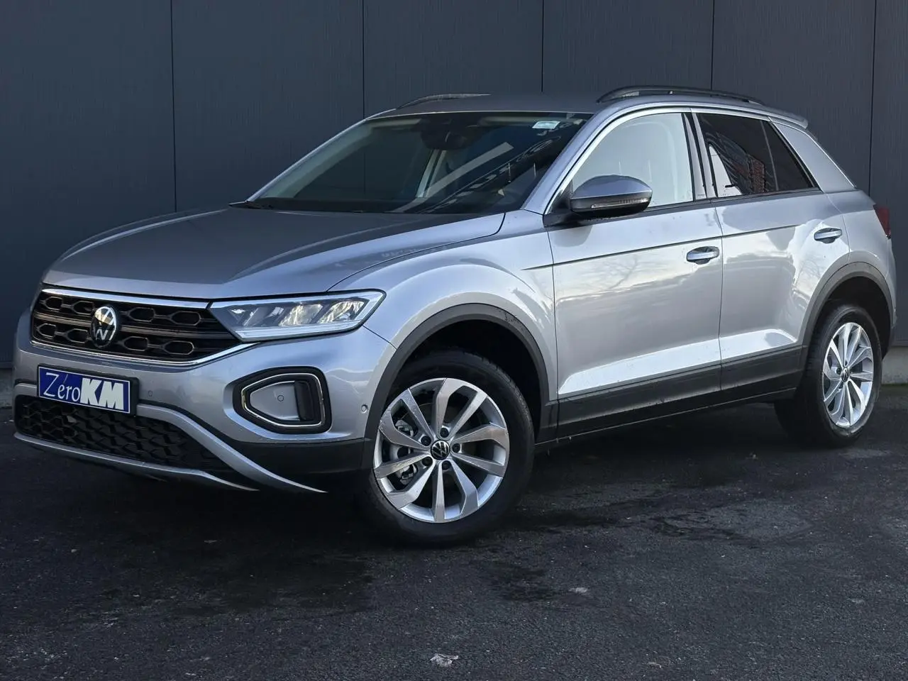 Volkswagen T-Roc 1.5 TSI gris Indium, vue 3/4 avant droit, avec jantes alliage et calandre noire.