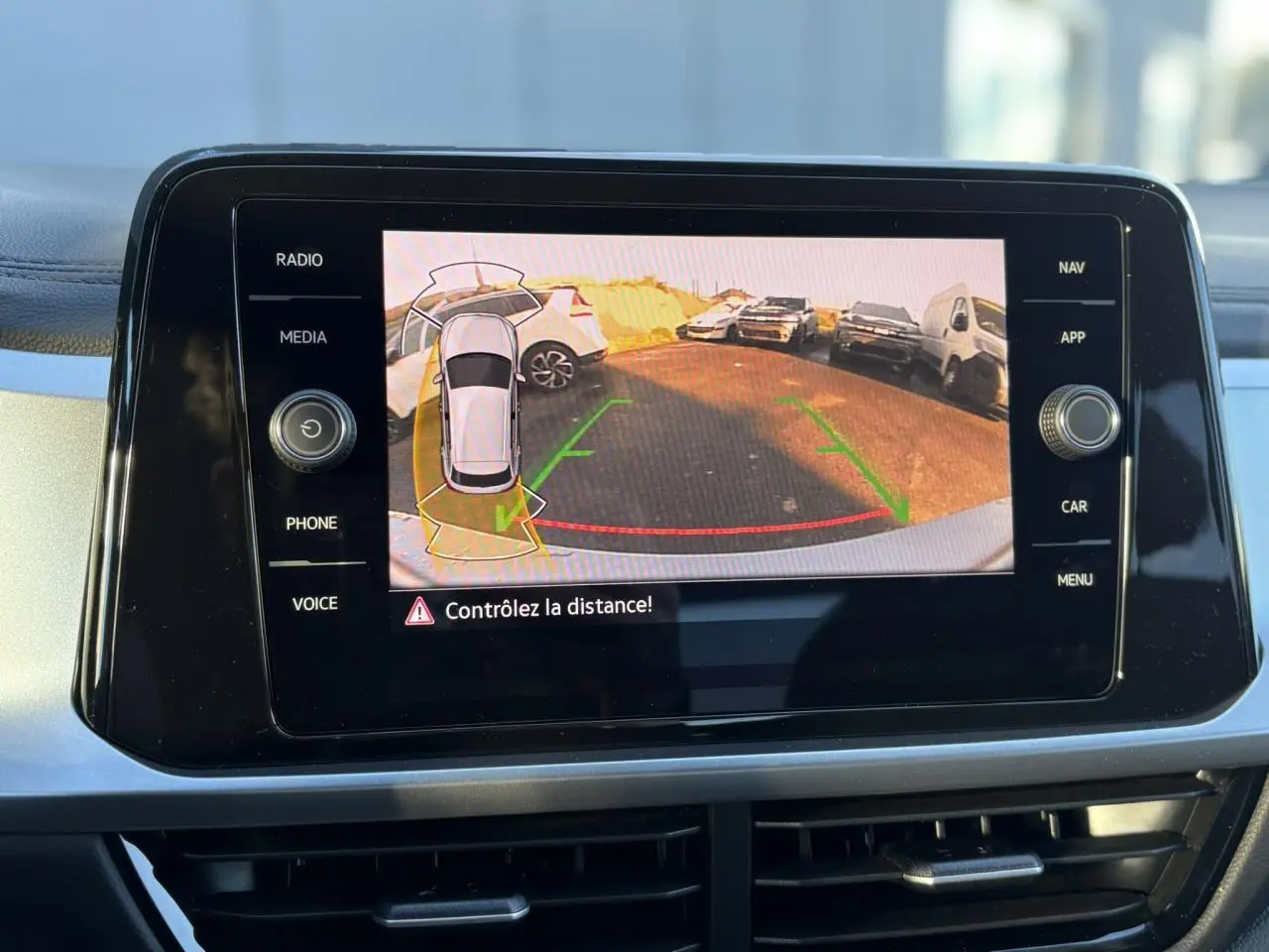 Écran tactile intérieur affichant la caméra de recul du Volkswagen T-Roc gris Indium, avec guidage de trajectoire verte et rouge.
