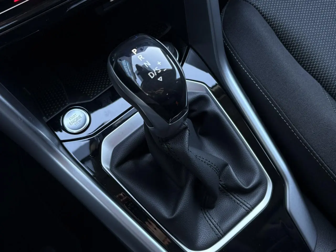 Gros plan sur la commande de boîte automatique noire et le bouton start/stop dans l’habitacle du Volkswagen T-Roc gris.