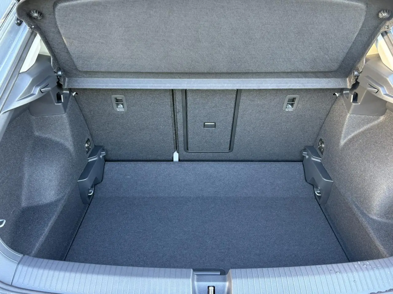 Vue plongeante sur le coffre spacieux et propre du Volkswagen T-Roc gris Indium, avec plancher plat et banquette arrière rabattable.