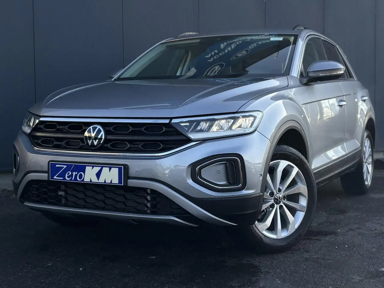Volkswagen T-Roc gris Indium en 3/4 avant droit, avec calandre noire et jantes alliage visibles.