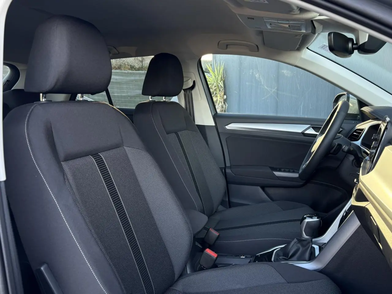 Vue intérieure côté droit des sièges avant noirs du Volkswagen T-Roc 1.5 TSI 150 DSG Life 30 Years avec volant multifonction.