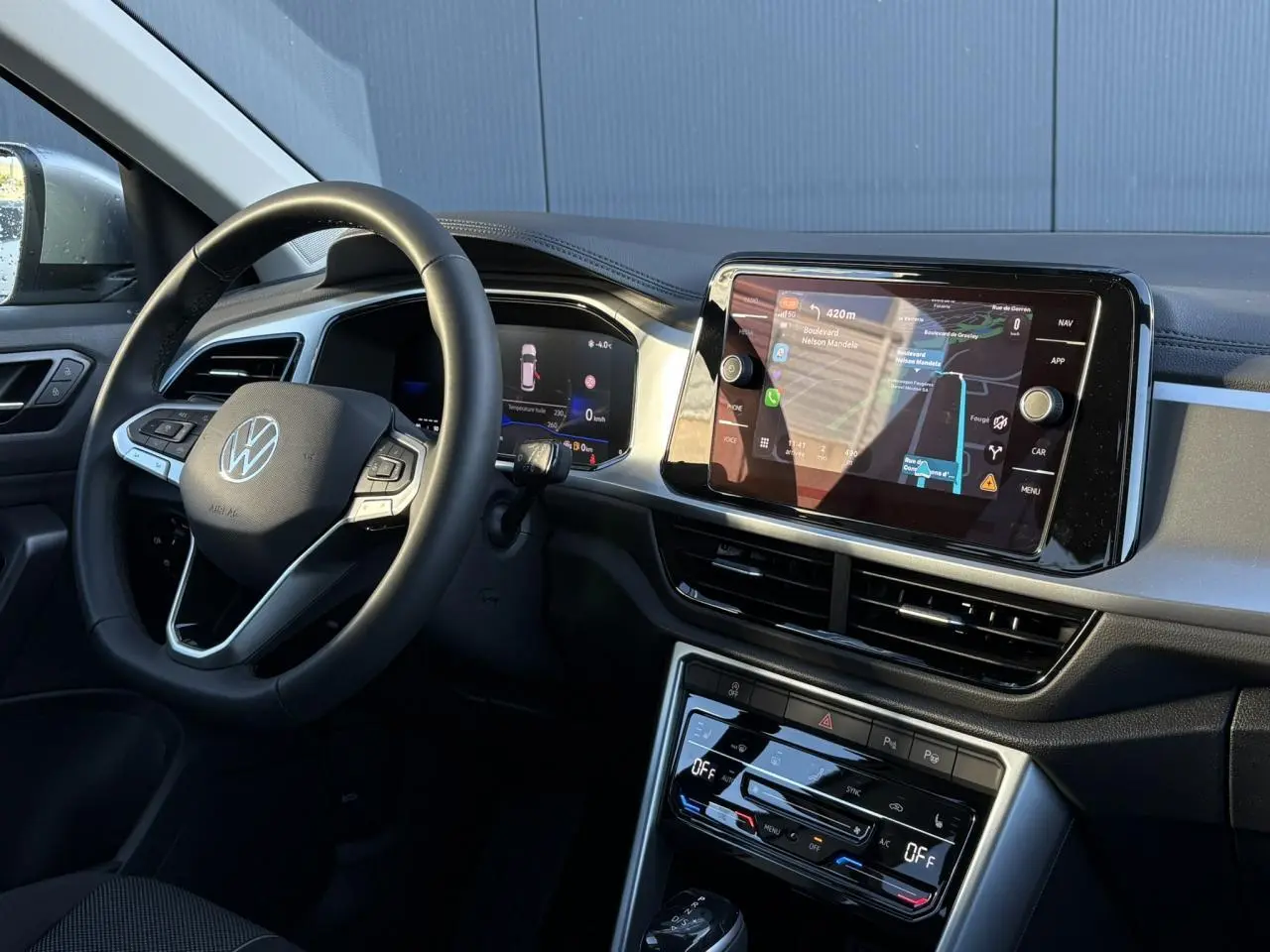 Vue intérieure côté conducteur du Volkswagen T-Roc gris Indium, mettant en valeur le volant multifonction et l'écran tactile central.