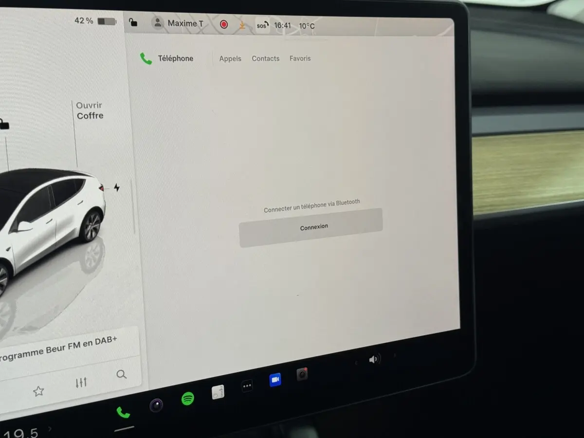 Écran tactile central affichant la connectivité Bluetooth dans l’habitacle d’une Tesla Model Y blanc, vue de près.