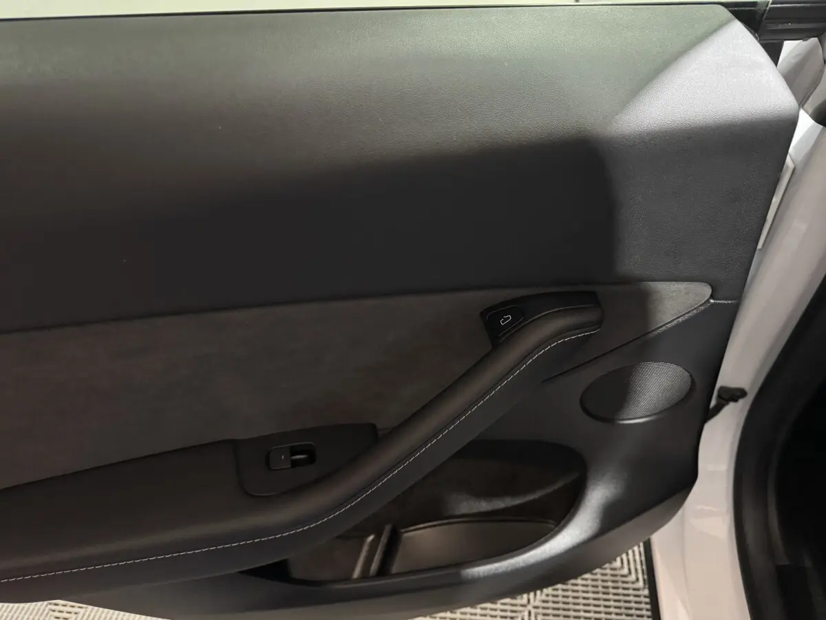 Gros plan sur la porte avant droite blanche d’un Tesla Model Y 2022, avec garniture noire et poignée intégrée.