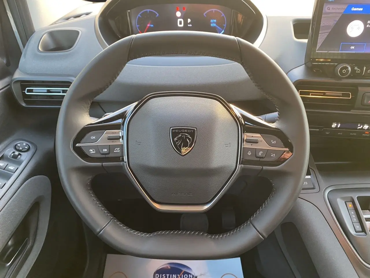 Vue rapprochée du volant cuir noir du Peugeot Rifter 2026 avec tableau de bord numérique et écran tactile central.