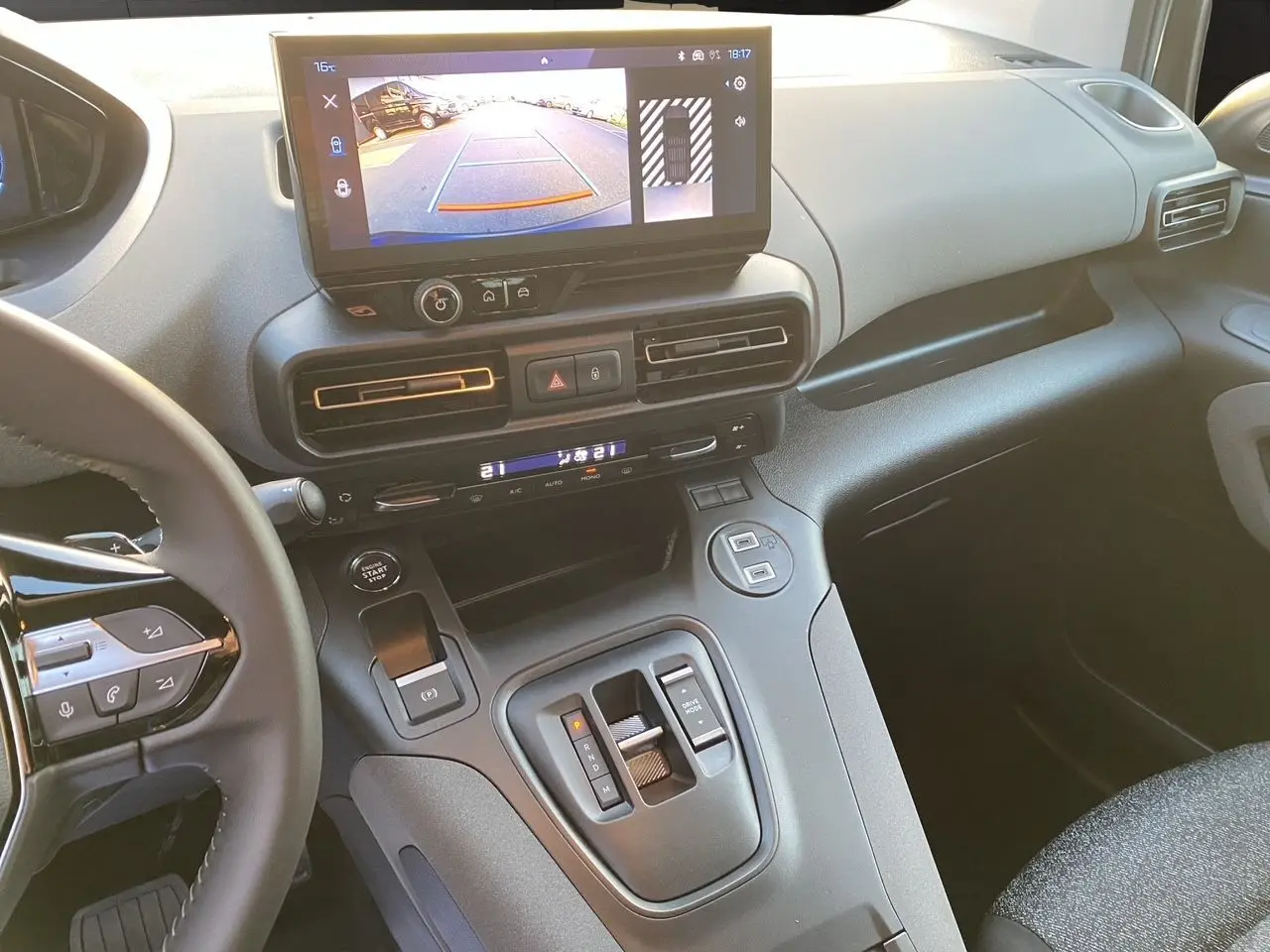 Vue intérieure du tableau de bord et console centrale du Peugeot Rifter gris acier, avec écran tactile et caméra de recul affichée.