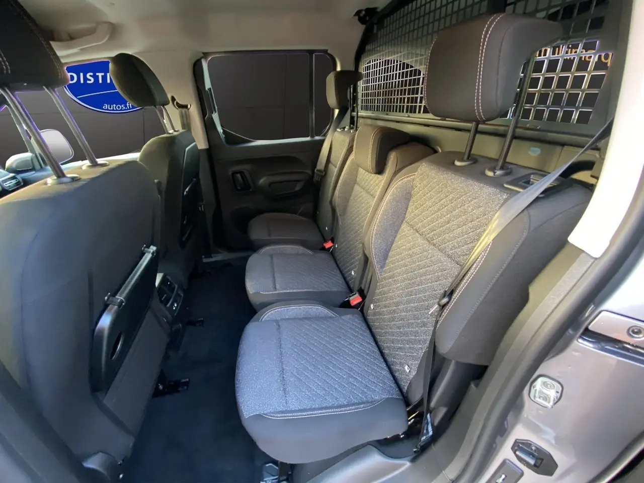 Vue intérieure côté droit sur les sièges arrière gris avec grille de séparation du Peugeot Rifter N1 M 2026.