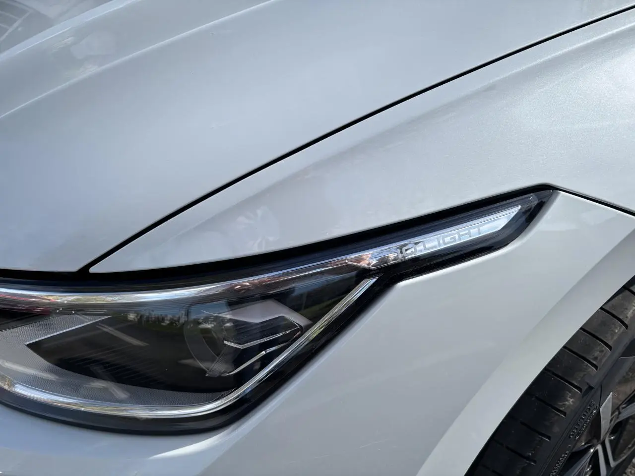 Gros plan sur le phare avant droit blanc de la Volkswagen Golf 1.5 eTSI Edition 50 2024 avec jante noire visible.