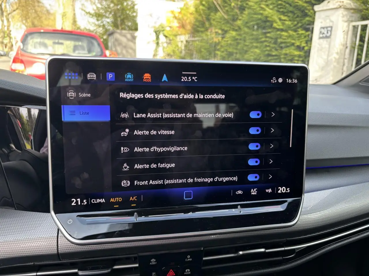 Écran tactile central de la Volkswagen Golf blanche 2024, vue intérieure sur les aides à la conduite activées.