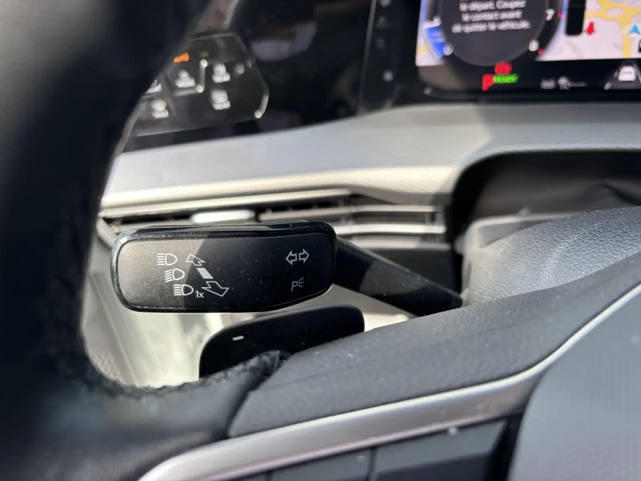 Gros plan sur la manette de clignotant noire dans l’habitacle blanc d’une Volkswagen Golf 1.5 eTSI 2024.