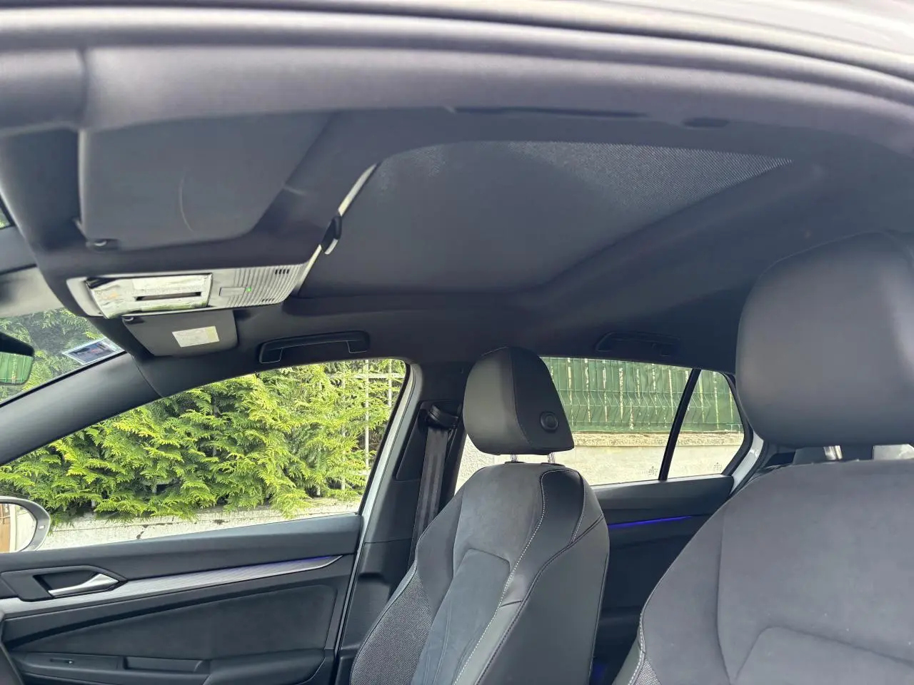 Vue intérieure de la Volkswagen Golf 1.5 eTSI Edition 50, montrant les sièges avant en tissu et cuir noir avec éclairage d'ambiance bleu.