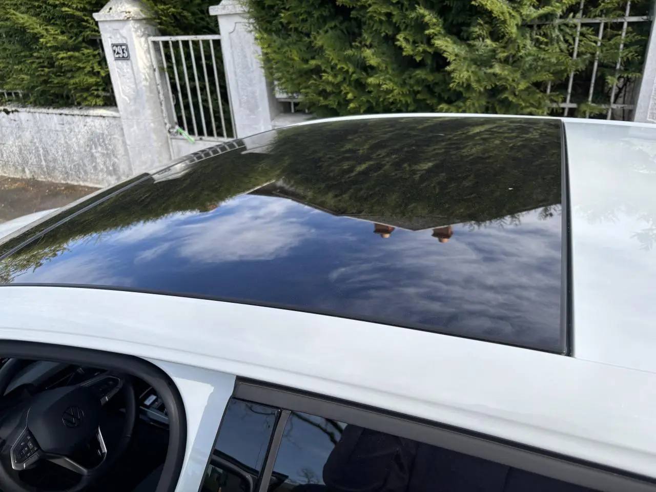 Toit panoramique en verre noir sur une Volkswagen Golf blanche 2024, vue partielle du côté gauche avec volant visible.