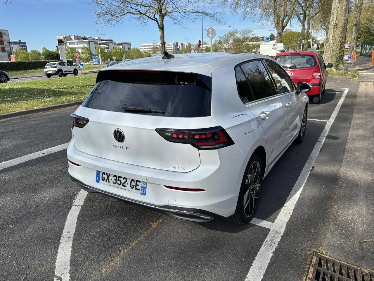 Vue 3/4 arrière droite d'une Volkswagen Golf blanche 1.5 eTSI Edition 50 2024, garée sur rue avec vitres teintées.
