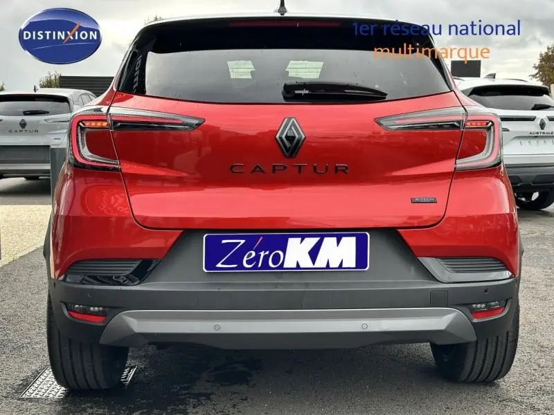 Vue arrière du Renault Captur 2025 rouge Flamme avec toit noir, badge hybride et plaque Zéro KM visible.