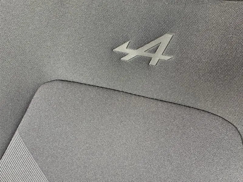 Détail de l'intérieur avec le logo Alpine en relief sur un tissu gris, typique du Renault Captur Esprit Alpine 2025.