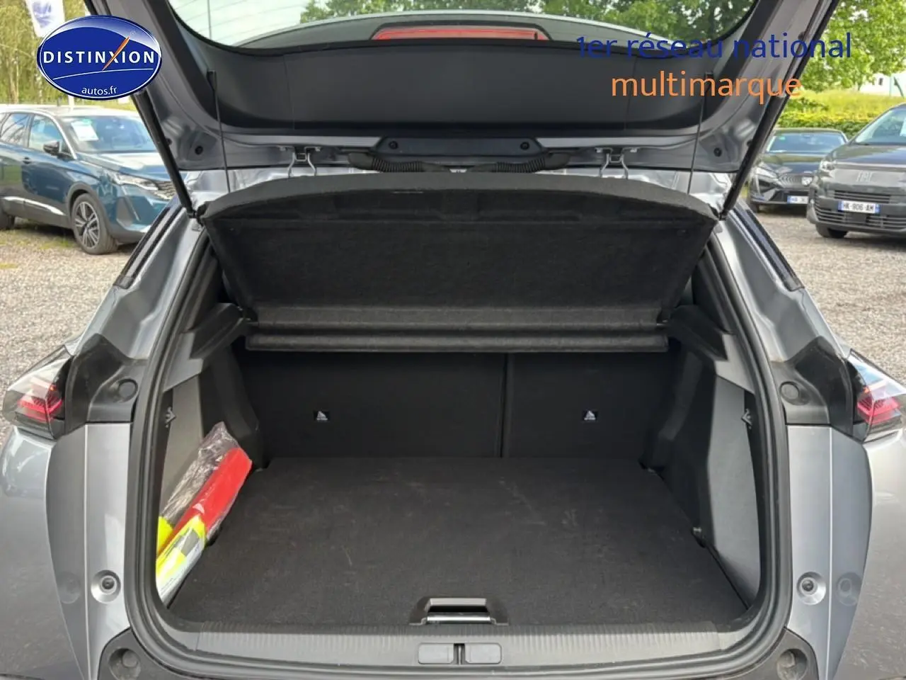 Coffre ouvert vu de l'arrière d'un Peugeot 2008 gris artense avec intérieur noir et cache-bagages relevé.