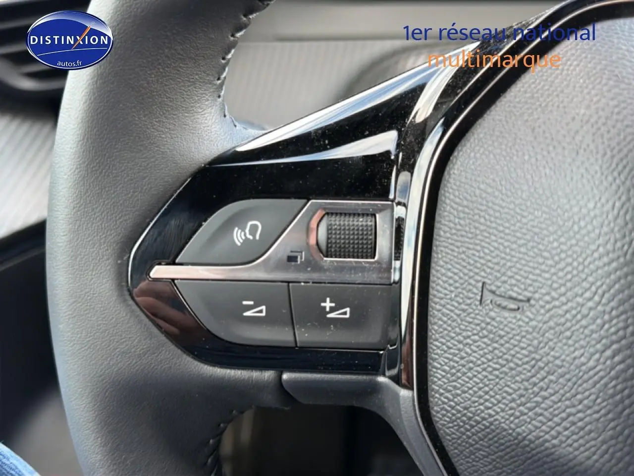 Gros plan sur les commandes gauche du volant cuir du Peugeot 2008 gris artense, boutons multifonctions visibles.