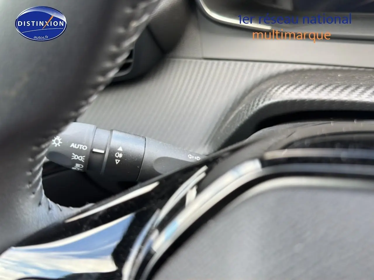 Gros plan sur la commande des phares à gauche du volant dans l’habitacle gris du Peugeot 2008 1.2 100 Allure 2025.
