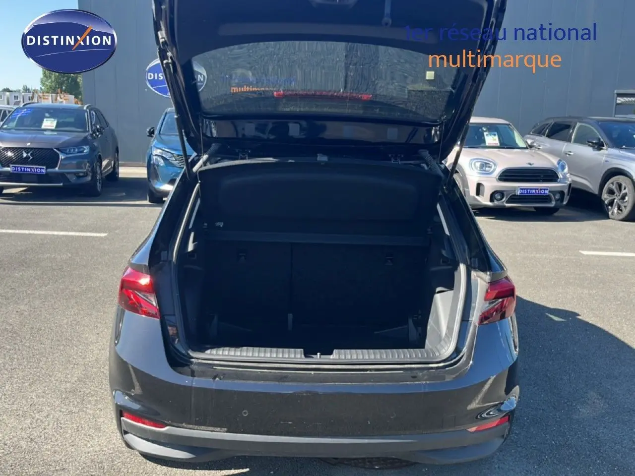 Vue arrière d’une Skoda Fabia 1.0 TSI 95CH Selection noire avec coffre ouvert sur parking extérieur.