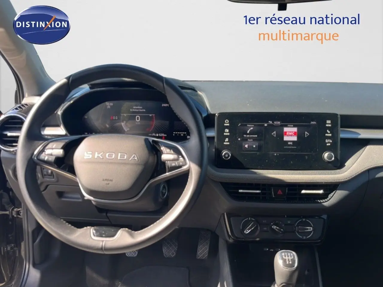 Vue intérieure centrée sur le volant SKODA et tableau de bord avec écran tactile, ambiance sobre en noir magique métal.