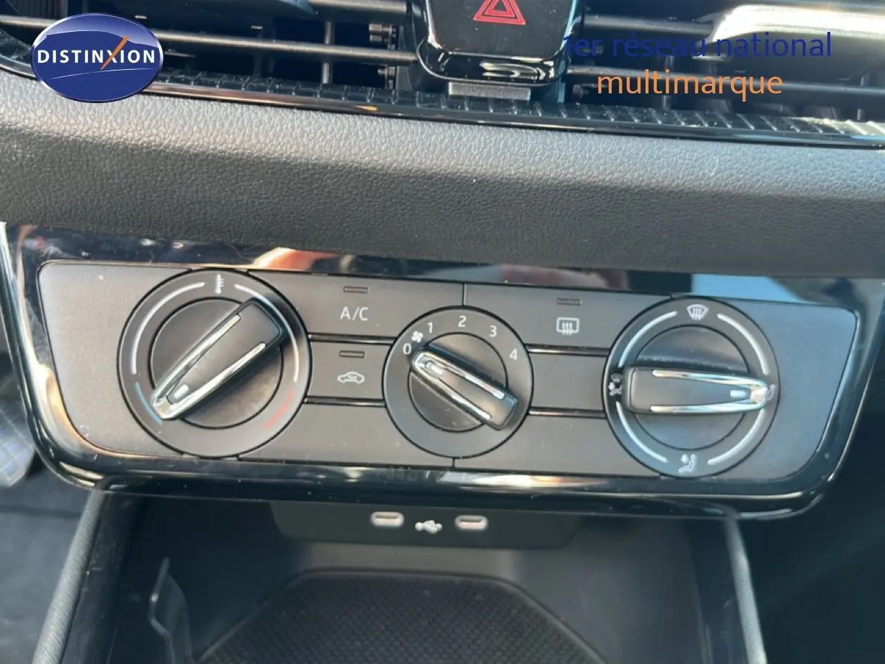 Gros plan sur les commandes de climatisation d’une Skoda Fabia noire, avec boutons rotatifs et ports USB visibles en dessous.