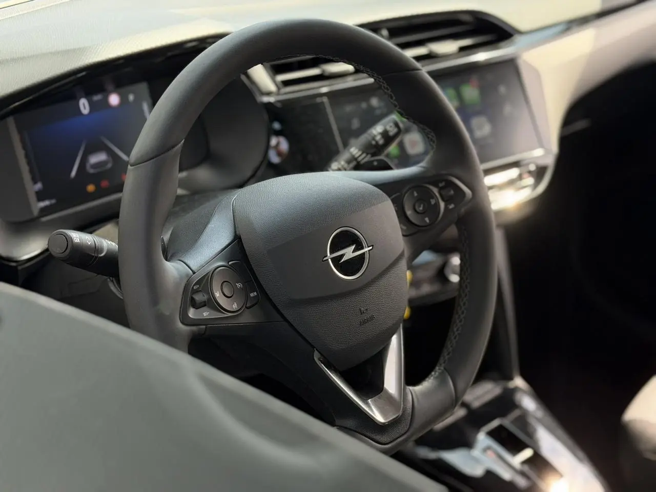 Vue intérieure centrée sur le volant multifonction noir de l’Opel Corsa 2025 avec écran tactile en arrière-plan flou.