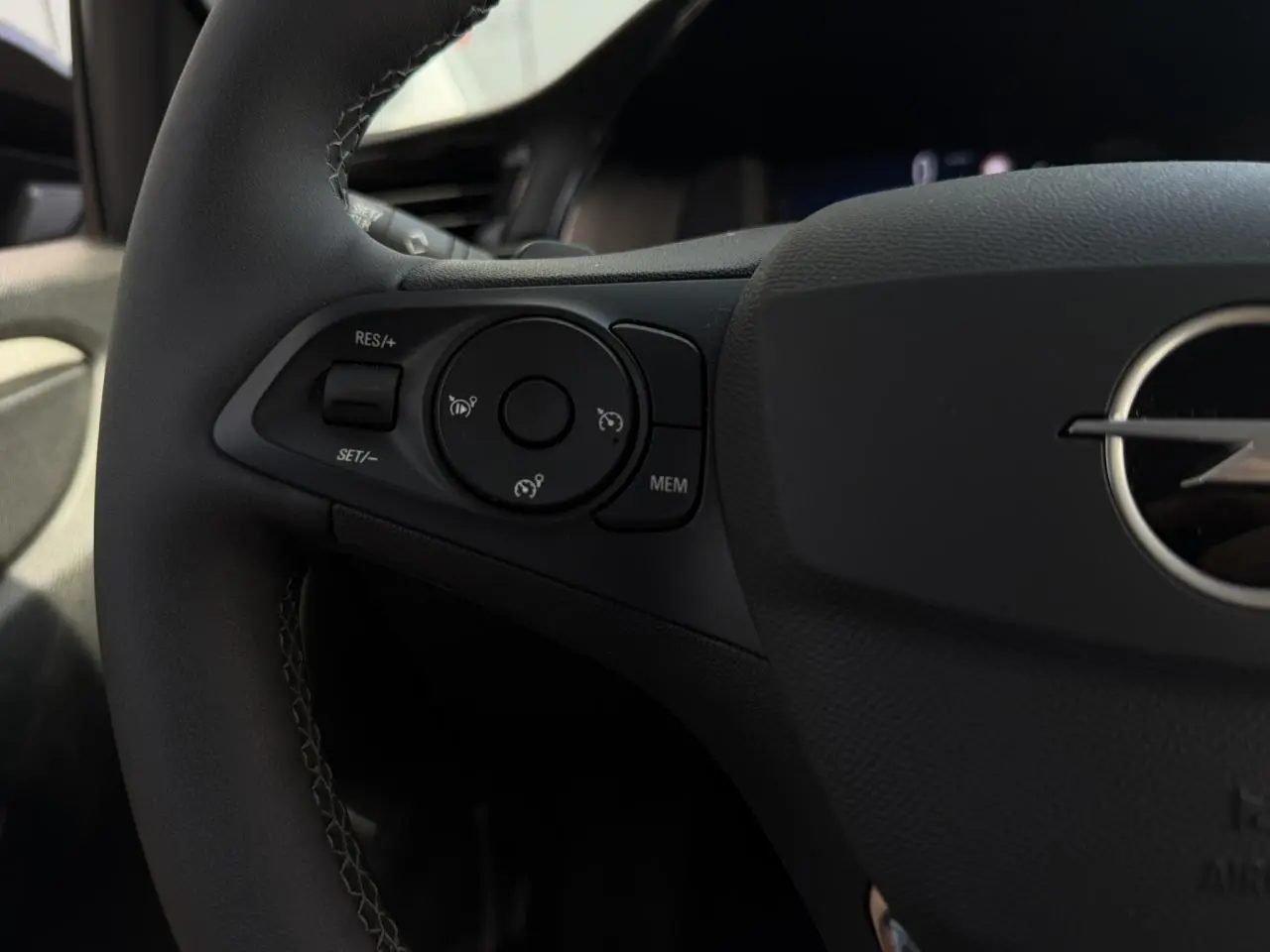 Gros plan sur les commandes de régulateur de vitesse à gauche du volant noir de l’Opel Corsa 2025.