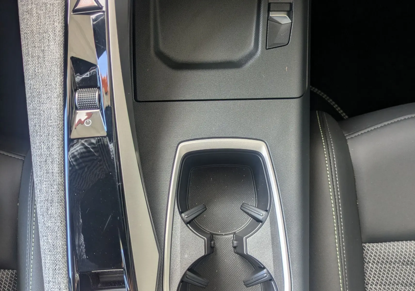 Vue plongeante sur la console centrale noire du Peugeot 3008 Hybrid 145 GT avec porte-gobelets et commandes intégrées.