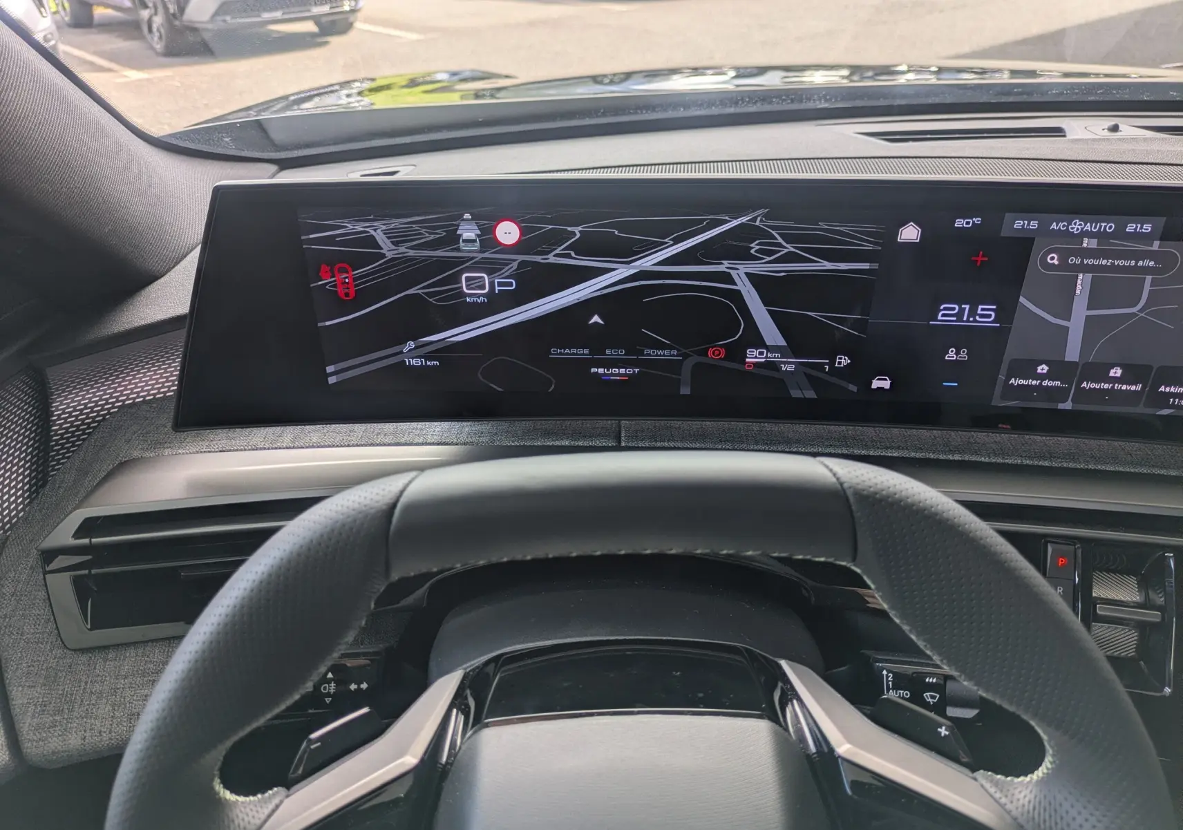 Vue intérieure du tableau de bord du Peugeot 3008 Hybrid 145 GT 2025, écran numérique large avec navigation et climatisation affichée.