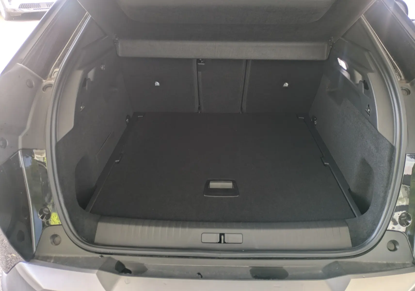 Coffre ouvert d’un Peugeot 3008 Hybrid 145 noir, vue arrière montrant un espace de chargement propre et spacieux.