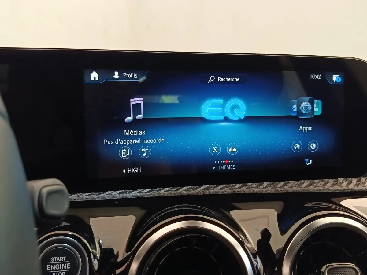 Vue rapprochée de l'écran tactile multimédia et des aérateurs ronds du tableau de bord d'une Mercedes Classe A noire.