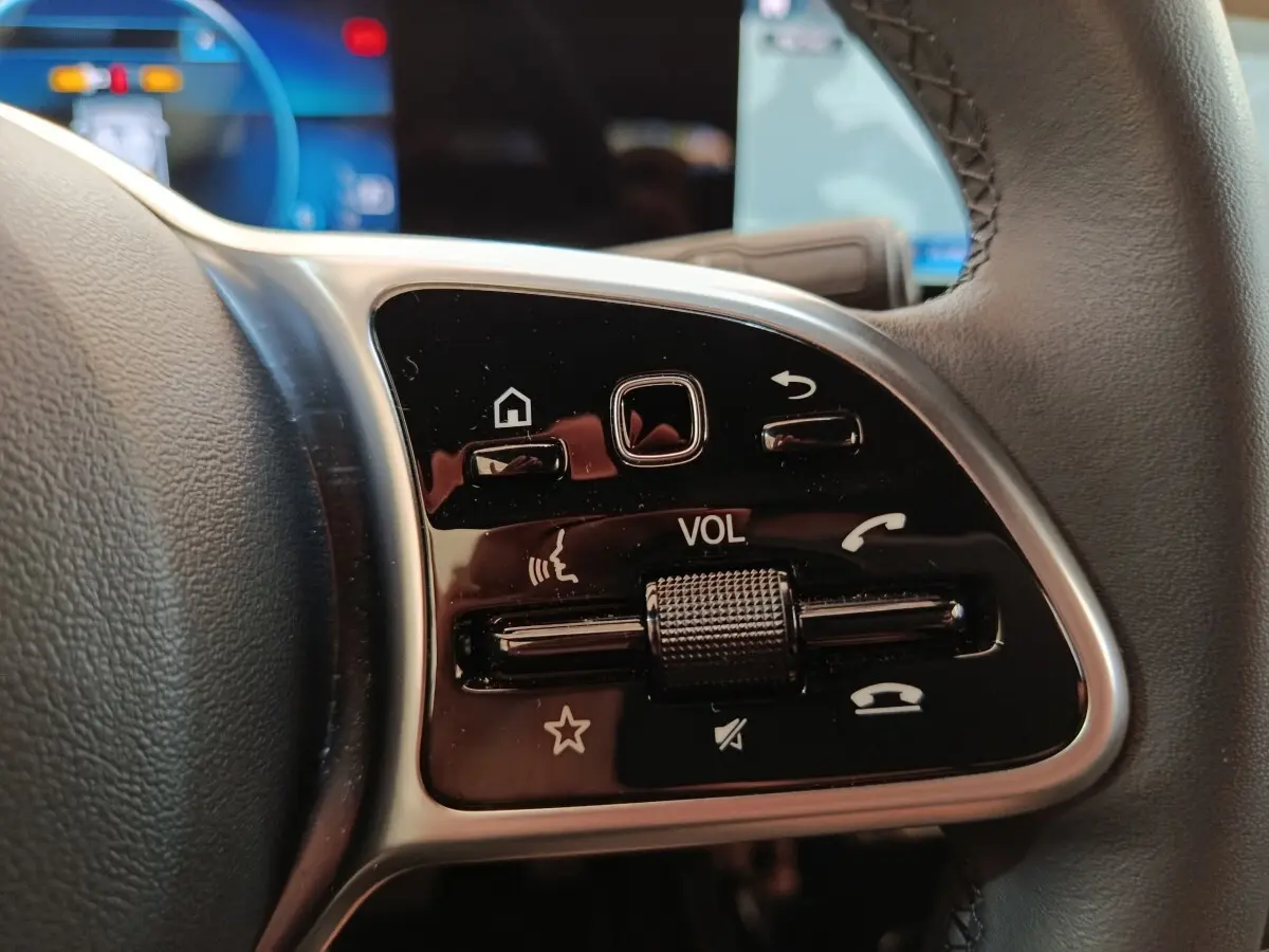 Gros plan sur les commandes multifonctions en cuir du volant côté gauche d’une Mercedes Classe A noire 2022.
