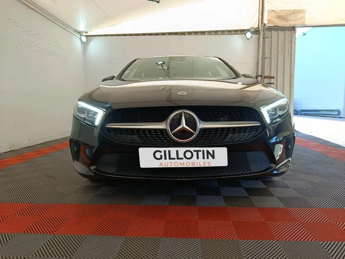 Vue frontale d'une Mercedes Classe A noire 2022 avec phares LED allumés dans un garage éclairé.
