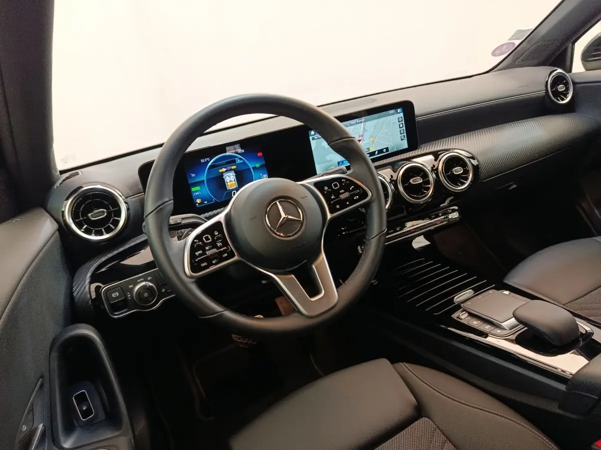 Vue intérieure du poste de conduite de la Mercedes Classe A noire, avec volant cuir multifonctions et écran tactile de navigation.