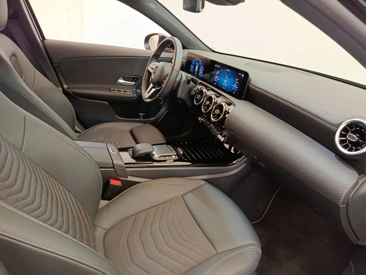 Vue intérieure côté conducteur de la Mercedes Classe A 250 e Business Line 2022 avec sièges cuir noirs et tableau de bord numérique.