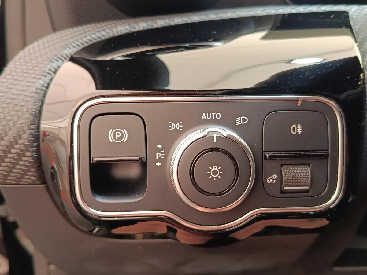 Gros plan sur le panneau de commandes d’éclairage et frein à main électrique de la Mercedes Classe A noire.