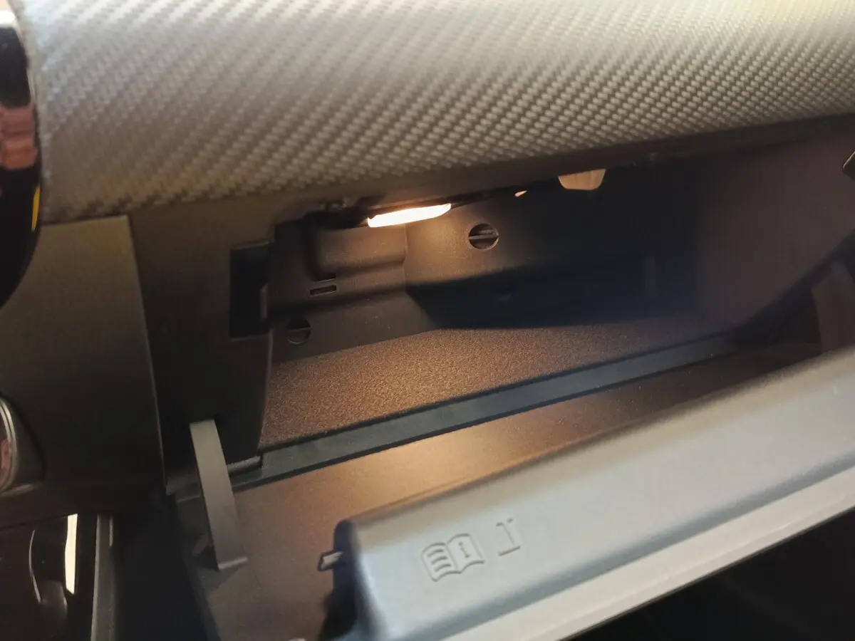 Intérieur de la boîte à gants ouverte de la Mercedes Classe A 250 e Business Line noire, éclairage intérieur visible.