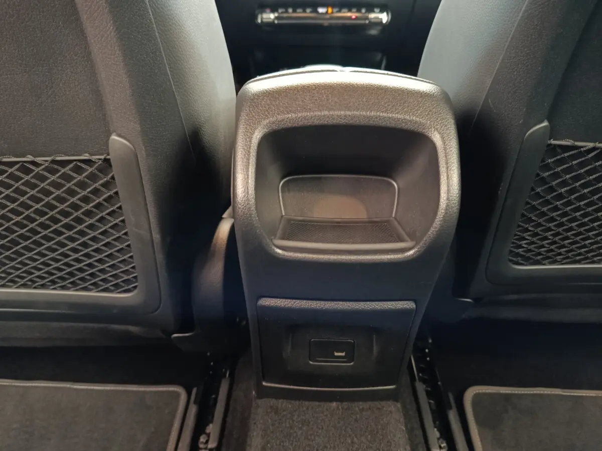 Vue rapprochée de la console centrale arrière noire entre les sièges avant d'une Mercedes Classe A 250 e Business Line.