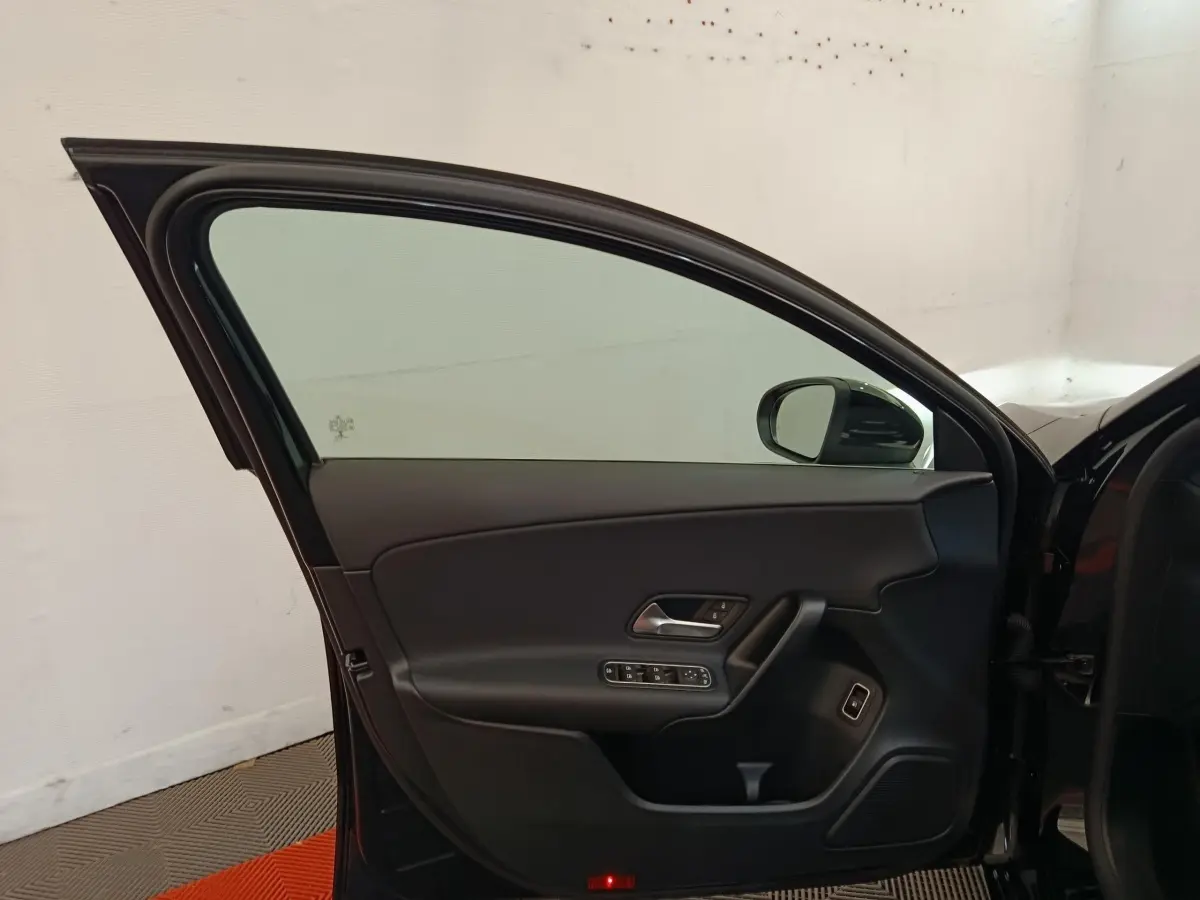 Vue intérieure de la porte avant gauche noire d'une Mercedes Classe A 250 e Business Line 2022, avec commandes électriques.