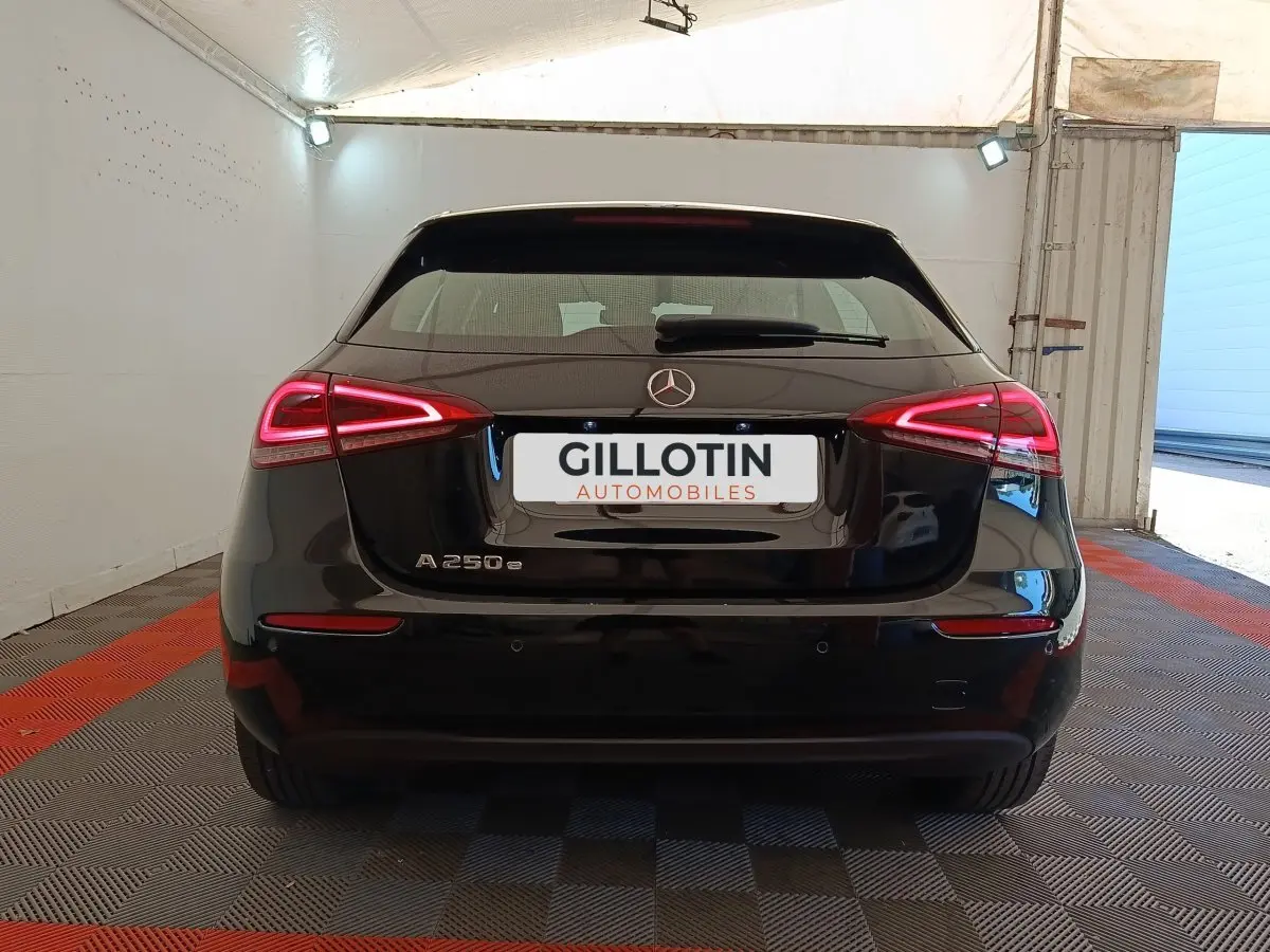 Vue arrière d'une Mercedes Classe A 250 e Business Line noire avec feux LED allumés dans un garage.
